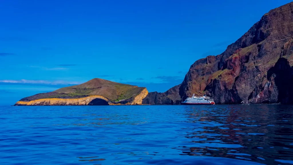 Coastal view of Isabela Island in the Galápagos, with ocean, sand, and volcanic terrain.