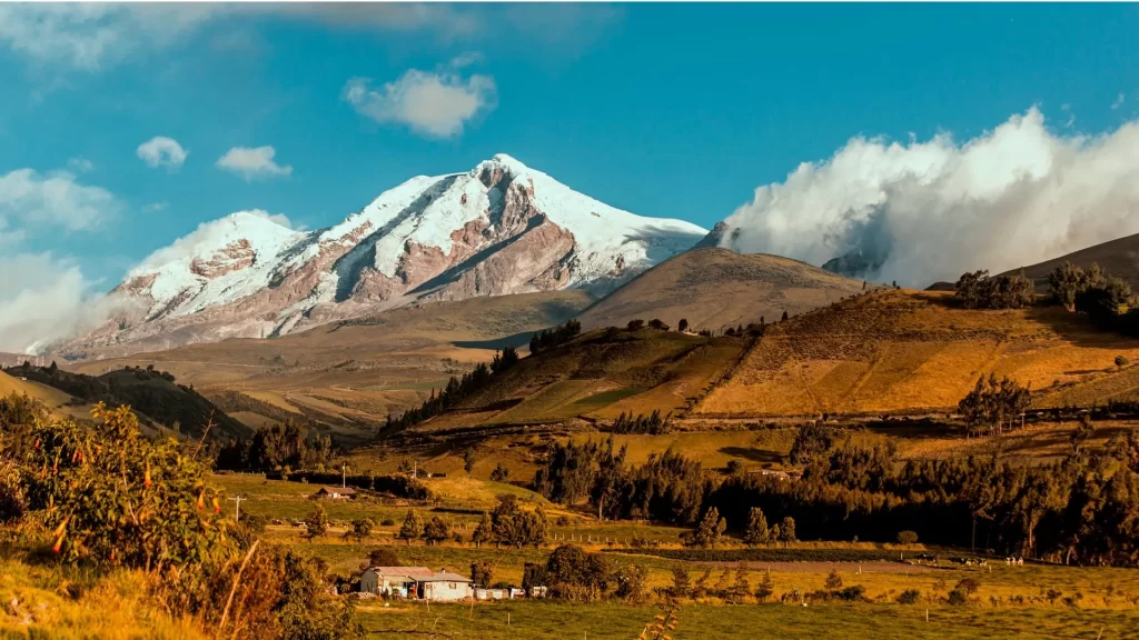 The image shows a sunset in La Chimba, Cayambe, Ecuador, with the snow-capped Cayambe Volcano.