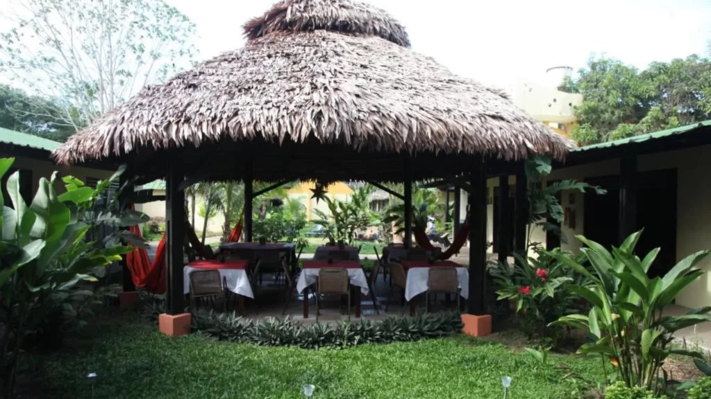Outdoor dining area with thatched-roof maloca, hammocks, and tropical vegetation at Amazon Bed & Breakfast, Leticia.