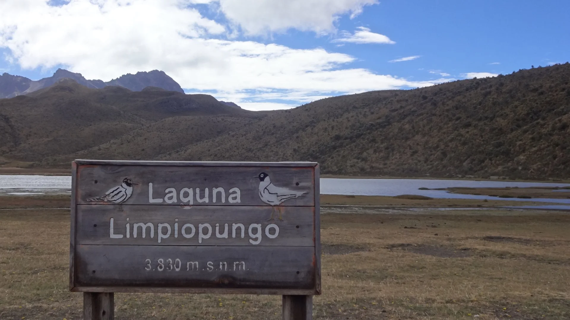 Sign of Limpiopungo Lagoon in Cotopaxi National Park, Ecuador, with the lagoon and Andean landscape in the background.