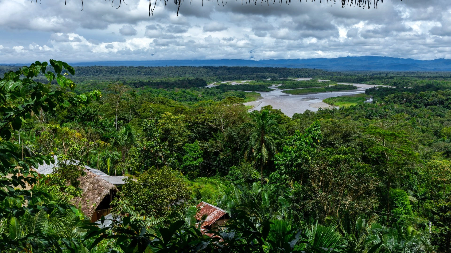 Panoramic view of the Ecuadorian Amazon with the Pastaza River winding through dense rainforest and indigenous houses.