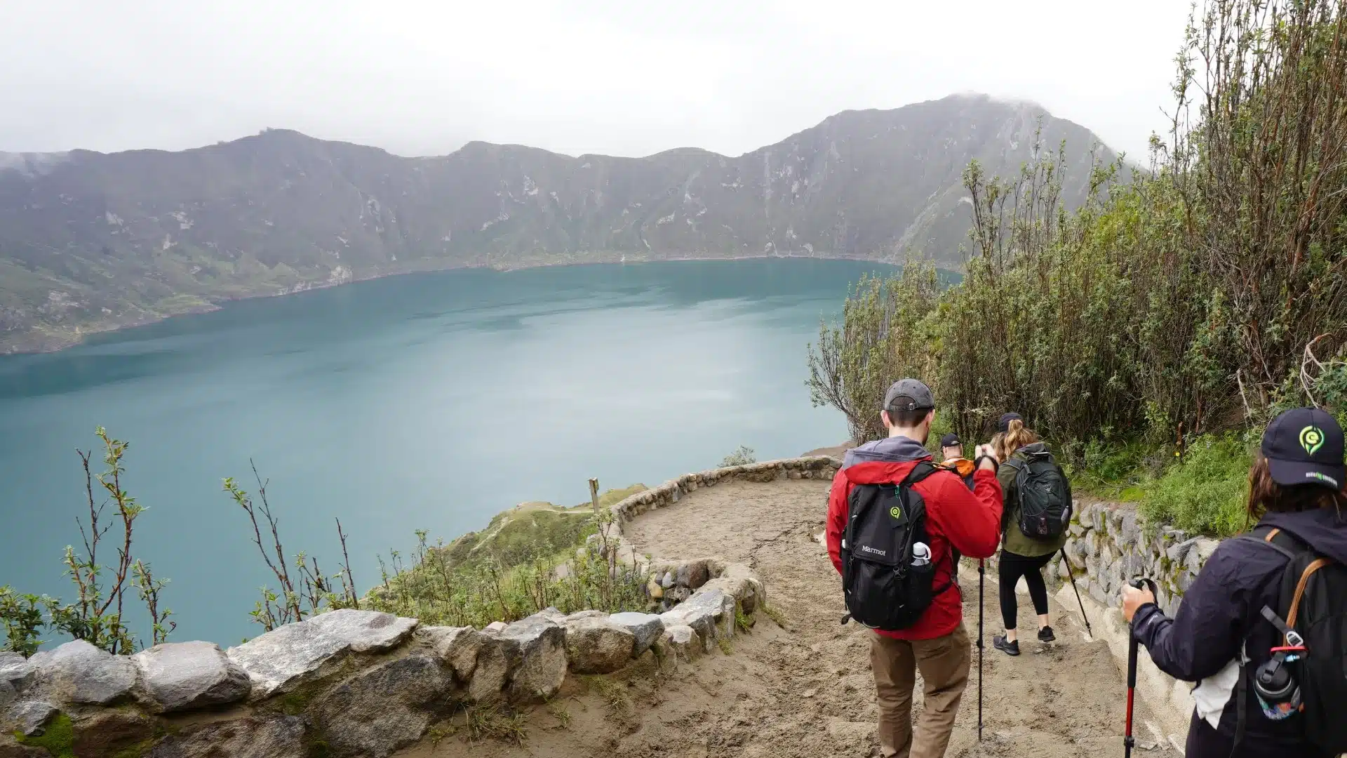 Panoramic view of Quilotoa Lagoon in Ecuador, with emerald-green crater waters and visitors enjoying the lookout points.