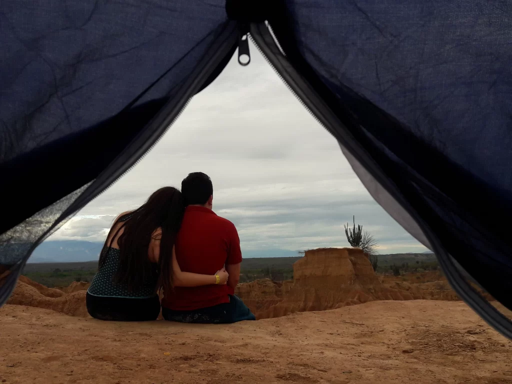 Couple sitting at the entrance of a tent overlooking the Tatacoa Desert landscape in Colombia.