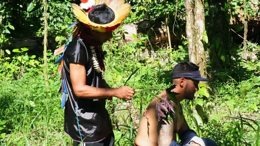 Cofán guide showing the medicinal use of nettles in the medicinal garden with a visitor-Ecuadorian Amazon responsible travel